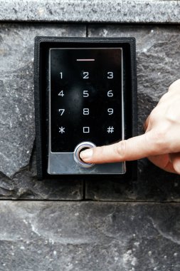 Taş bir duvarda, modern güvenlik teknolojisi ve erişim kontrol sistemlerindeki kullanıcı deneyimini gösteren gösterişli dijital bir tuş takımı ile yakın çekim.