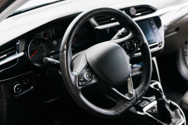 Bir arabanın iç mekanına ayrıntılı bir bakış, şık bir direksiyon ve gösterge panelini vurgulamak, modern tasarım elemanlarını ve otomotiv mühendisliğindeki gelişmiş teknolojiyi vurgulamak,