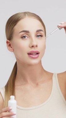 Kadın yüzüne serum sürüyor.