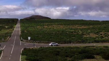 Araba tepelerden geçen dolambaçlı yolda gidiyor.
