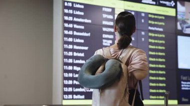 Havaalanındaki uçuş bilgilerine bakan kadın..