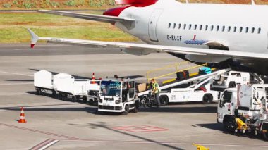Truck loading luggage on airplane at airport.