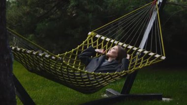 Yeşil çimenlerde hamakta dinlenen bir kadın