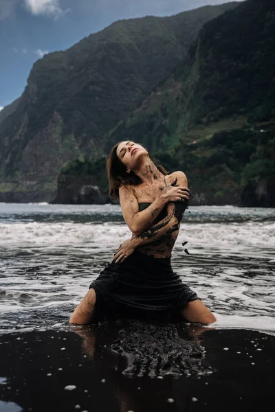 Kadın figürü okyanus dalgalarında diz çöker, doğal çevreyi barışçıl bir tavırla kucaklar, uçurumlar ve yeşillik çarpıcı bir zemin oluşturur, sükunet ve ahenk uyandırır.