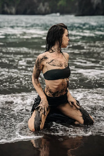 Suda diz çökmüş, çamurla süslenmiş kadın figürü, dalgalar nazikçe etrafta dolanıyor, doğanın, özgürlüğün ve kişisel yolculuğun temalarını anımsatıyor.