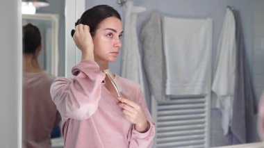 Banyodaki aynada saç ayarlayan kadın.