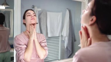 Banyodaki aynaya cilt bakımı yapan kadın.