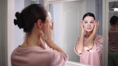 Banyo aynasına yüz maskesi takan bir kadın.