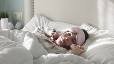 Kadın rahat bir yatakta huzur içinde uyuyor.