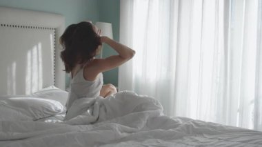 Sabah ışığında yatakta oturan bir kadın.