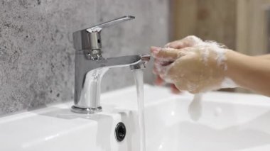 Modern lavaboda ellerini yıkayan biri..