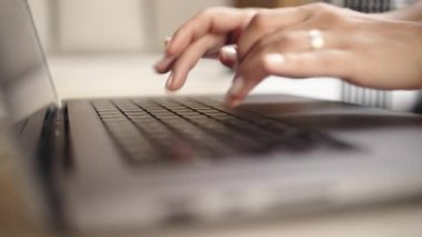 Evde dizüstü bilgisayarda yazı yazan kişi.