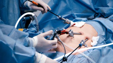 Tıbbi profesyoneller, steril bir ortamda gelişmiş araç ve teknikleri kullanarak, takım çalışmasını ve hassasiyetini vurgulayarak, minimal invazif bir ameliyata giriştiler.