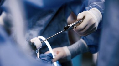 Cerrahi kıyafetli sağlık çalışanı, steril bir ortamda tıbbi prosedür sırasında profesyonellik ve uzmanlığı vurgulayan özel araçlar kullanıyor