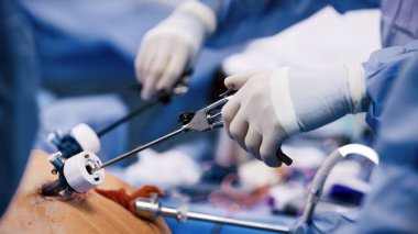 Eldiven giyen sağlık çalışanı, hasta modeli üzerinde uzmanlaşmış aletlerle cerrahi müdahalede bulunur. Steril bir klinik ortamında becerileri ve odaklanmayı ön plana çıkarır.