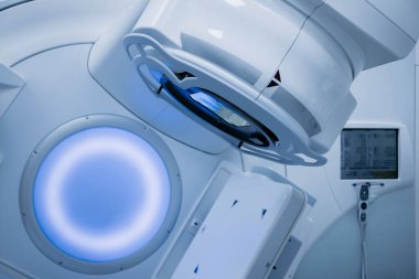 Onkoloji tedavisi için gelişmiş doğrusal hızlandırıcı, modern tasarım ve teknolojinin sergilenmesi, ortam aydınlatması ve sofistike tıbbi ekipmanların bulunduğu klinik bir ortamda ayarlanıyor.