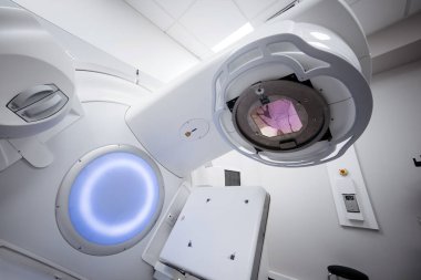 Onkoloji tedavisi için gelişmiş doğrusal hızlandırıcı, modern bir tasarım ve aydınlatılmış elementler içeriyor, hassasiyet ve hasta bakımına odaklanmış klinik bir ortamda ayarlanıyor