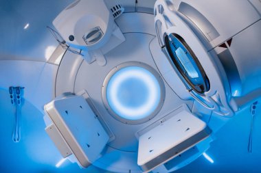 Doğrusal hızlandırıcıya sahip onkoloji tedavi odası, aydınlatılmış yüzeyler ve modern tasarım sergileniyor, kanser tedavisi gören hastalar için sakinleştirici bir atmosfer yaratılıyor.