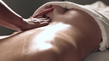 Masaj terapisti ve kadın vücut masajı yaptırıyor.