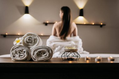 Spa sahnesi havlular, mumlar ve sakin bir ortam, masaj yaptıran bir kadın, rahatlatıcı bir ortamda rahatlık ve refahı teşvik ediyor.