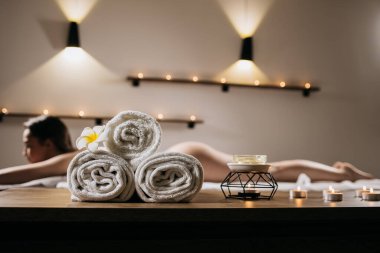 Huzurlu spa ortamları beyaz havlular, yumuşak mum ışığı ve rahatlatıcı bir masaj alan bir kadın rahatlama ve gençleşme için huzurlu bir ortam yaratıyor.
