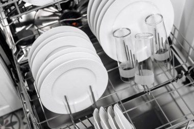 Temiz beyaz tabaklar ve bardaklar düzgün bir şekilde bulaşık makinesine yerleştirilmiş, düzenli düzeni ve modern tasarımı vurguluyor, verimli mutfak kullanımı için mükemmel.