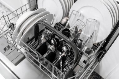 Düzenli tabak, bardak ve çatal bıçaklarla dolu bulaşık makinesi, çağdaş bir mutfak ortamındaki düzenli düzen ve işlevselliği vurguluyor