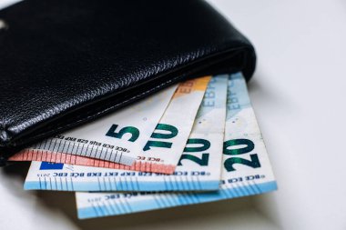 Açık siyah cüzdan çeşitli banknotlar, canlı renkler ve dokular gösteren, günlük hayatta para birimi ve mali yönetimi temsil eden sergiler