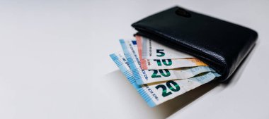 Çeşitli banknotlarda çeşitli banknotları gösteren, hafif bir zeminde dinlenen, finans ve para yönetimi temaları gösteren siyah cüzdan