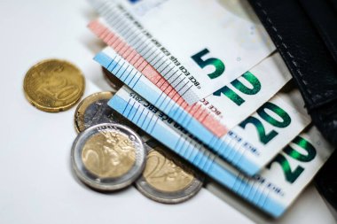 Çeşitli para birimleri ve paralar bir cüzdana düzgünce yerleştirilir, farklı değerler ve malzemeler vurgulanır, para yönetiminin görsel bir temsili oluşturulur