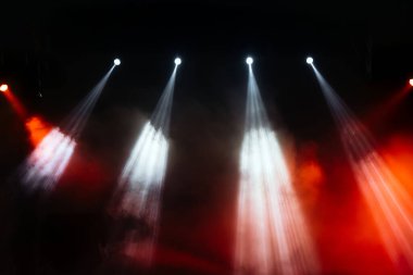 Sahne ışıkları kırmızı, beyaz ve turuncu ışınlar yansıtıyor dumanlı bir ortamda, atmosferi yükselterek konserler ve tiyatro performansları için