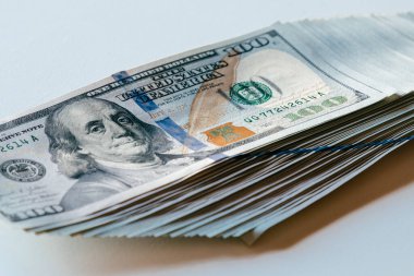 Düzgünce düzenlenmiş yüz dolarlık banknotlar. Karmaşık tasarım detaylarını ve dokularını vurgulayarak finansal başarıyı ve bolluğu sembolize ediyor.