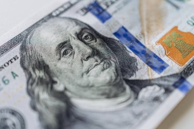 Portreyi, güvenlik özelliklerini ve canlı renkleri vurgulayan, para ve ekonomik işlemleri sembolize eden 100 dolarlık banknotun ayrıntılı görüntüsü