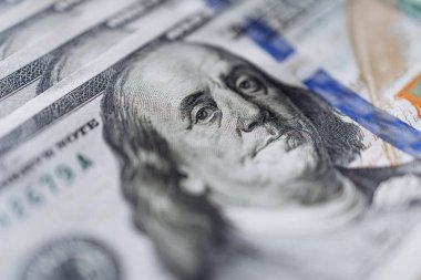 Modern ekonomide zenginlik ve finansal işlemleri temsil eden, karmaşık tasarım ve canlı renkleri vurgulayan, 100 dolarlık banknotun ayrıntılı görüntüsü