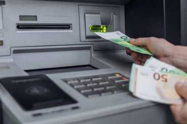 Para çekmek için ATM kullanan kişi, çeşitli banknotlar tutuyor, makinenin tuş takımı ile görünür ve görüntüleme,