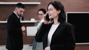 Üç iş adamı konuşuyor, cep telefonu olan bir kadın.