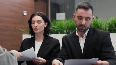 Ofiste belgeleri tartışan üç işadamı.