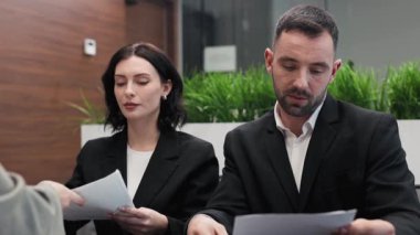 Ofiste belgeleri tartışan üç işadamı.