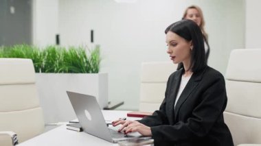 Laptop ve cep telefonuyla modern bir ofiste çalışan güzel iş kadınları.