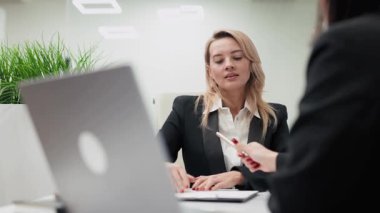 Modern bir ofiste çalışan iki iş kadını ofiste iş stratejilerini tartışıyor..