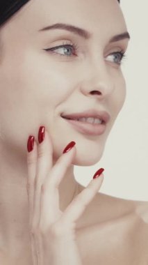 Koyu saçlı, sağlıklı cilt ve kırmızı manikür gösteren güzel bir kadın..
