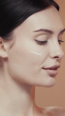 Aplikatörle beyaz yüz kremi süren bir kadının yakın plan portresi.