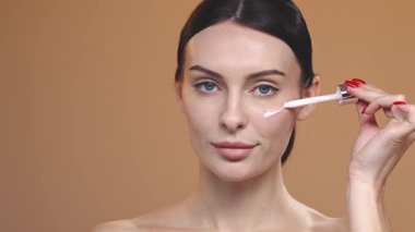 Güzel bir kadın parlayan cilt için yüz nemlendirici sürüyor. Güzellik rutini, estetik yüz bakımı..