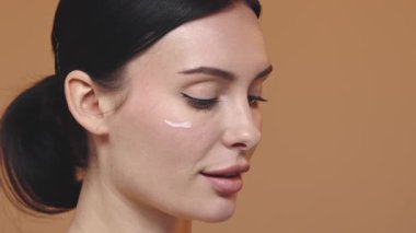 Güzel bir kadın parlayan cilt için yüz nemlendirici sürüyor. Güzellik rutini, estetik yüz bakımı..