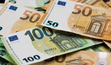 Düz bir yüzeyde gösterilen elli bin banknotun yer aldığı çeşitli Euro banknotları ayrıntılı tasarımlar ve canlı renkler sergiliyor