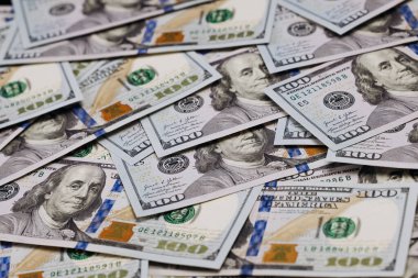 Düz bir yüzeye dizilmiş çoklu yüz dolarlık banknotların yakın plan görüntüsü, para biriminin ayrıntılı tasarımı ve renklerini vurguluyor