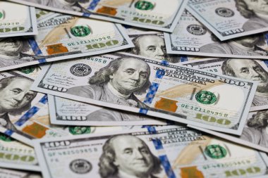 Düz bir yüzeye yerleştirilmiş birkaç yüz dolarlık banknotun yakın plan görüntüsü, para biriminin detaylı tasarım ve güvenlik özelliklerini vurguluyor