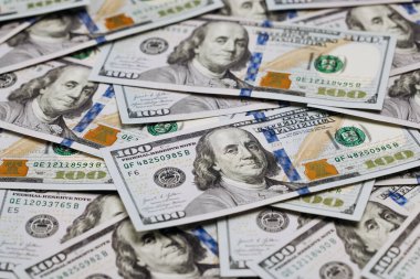 Düz bir yüzeye yerleştirilmiş birkaç yüz dolarlık banknotun yakın plan görüntüsü, para biriminin detaylı tasarımı ve güvenlik özelliklerini vurguluyor