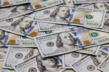 Düz bir yüzeye yerleştirilmiş birkaç yüz dolarlık banknotun yakın plan görüntüsü, para biriminin detaylı tasarımı ve güvenlik özelliklerini vurguluyor