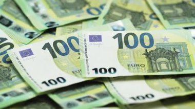 Bir yüzeyde 50 ve 100 banknotluk çeşitli avro banknotları sergilenirken, arka planda ek para birimi kısmen görülebilir